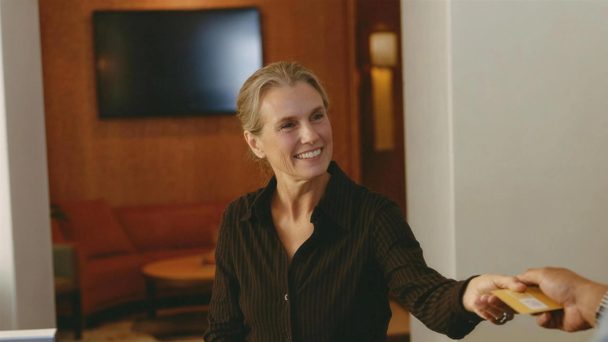 A woman at a hotel reception desk handing back her key card.