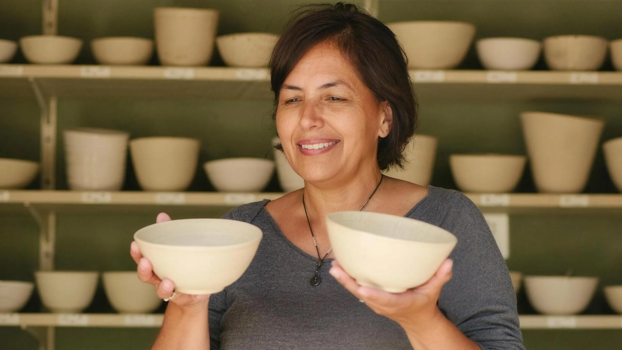 The owner of a ceramics shop holding a plain bowl in each hand, deciding which one stays on the shelf.